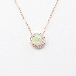 May include: A delicate rose gold necklace with a round opal pendant surrounded by a halo of sparkling white diamonds.