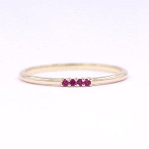 May include: A delicate gold band ring with four small ruby stones set in a row.