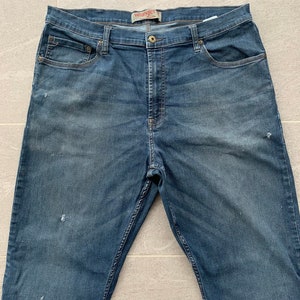 K&ouml;nnte beinhalten: Eine blaue Jeanshose mit dem Wrangler-Logo am hinteren Bund.