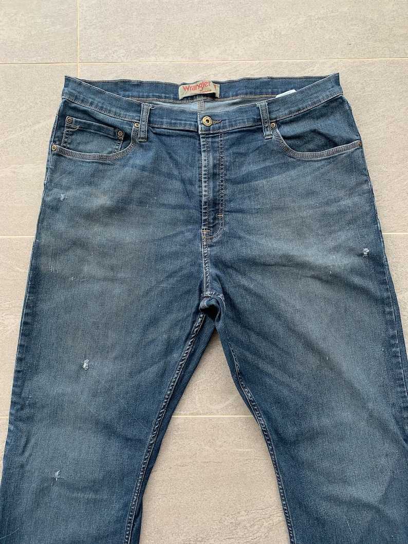 K&ouml;nnte beinhalten: Eine blaue Jeanshose mit dem Wrangler-Logo am hinteren Bund.