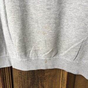 May include: Gray sweatshirt with a ribbed hem. The sweatshirt has a few light brown stains.
