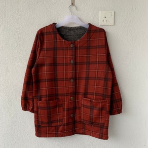 May include: A red and brown plaid jacket with a button-up front and two pockets. The jacket has a soft, fuzzy lining.