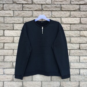 Puede incluir: Sudadera negra de manga larga con cremallera en el cuello.