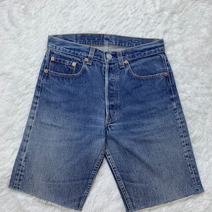 Puede incluir: Un par de pantalones cortos de mezclilla azul con dobladillo deshilachado. Los pantalones cortos tienen un diseño clásico de cinco bolsillos y cierre de botón.