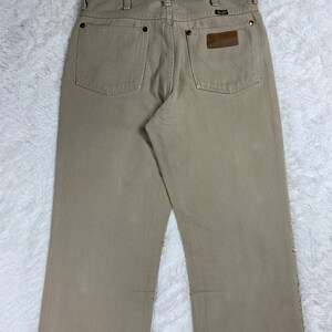 Op de afbeelding: Een lichtbruine Wrangler jeans met een leren patch op de achterzak.