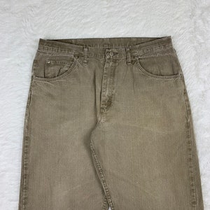 Op de afbeelding: Een paar bruine rechte jeans met een knoopsluiting en vijf zakken.