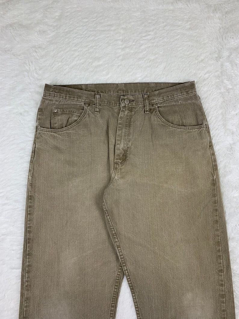 Op de afbeelding: Een paar bruine rechte jeans met een knoopsluiting en vijf zakken.