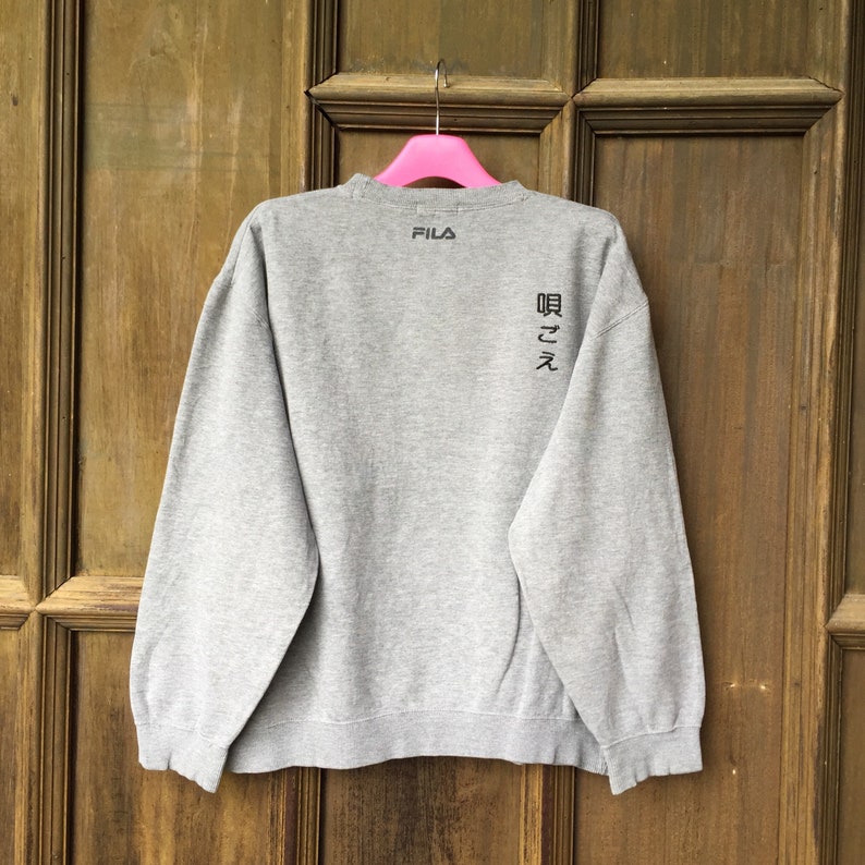 May include: Gray Fila sweatshirt with black text on the back that reads "Fila" and "Darkness".