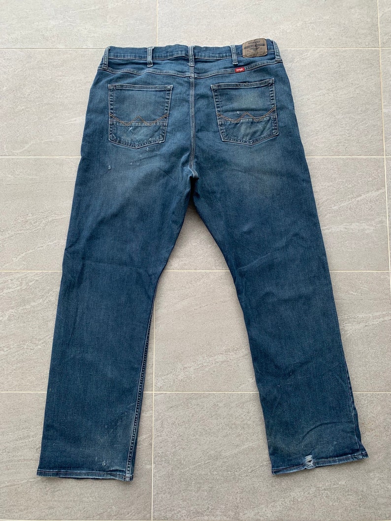 K&ouml;nnte beinhalten: Eine blaue Jeans mit ausgewaschenem Look und einem kleinen Markenetikett auf der Ges&auml;&szlig;tasche.