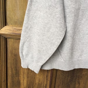 May include: Gray sweatshirt with a ribbed hem and cuffs.