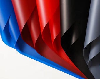 Könnte beinhalten: Nahaufnahme von fünf Blättern farbigem Papier, gefaltet und übereinander gelegt. Die Blätter sind blau, rot, schwarz und grau.