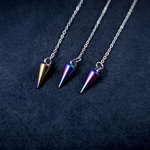 May include: Three iridescent metal pendulums with silver chains hanging against a dark blue background.