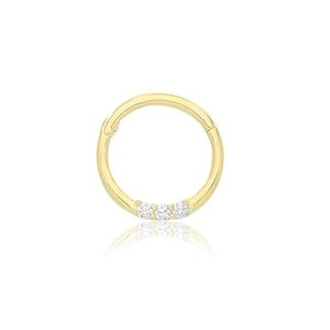 May include: A gold hoop earring with a row of three small clear gemstones.