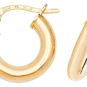 Puede incluir: Un par de pendientes de aro dorados. Los pendientes tienen un dise&ntilde;o cl&aacute;sico, con una superficie redondeada y pulida. El oro tiene una calidad brillante y reflectante. Los pendientes se muestran sobre un fondo blanco.