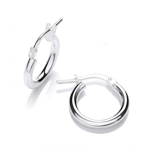 May include: A pair of silver hoop earrings with a simple, polished finish. The earrings are small and delicate, making them a versatile choice for everyday wear.