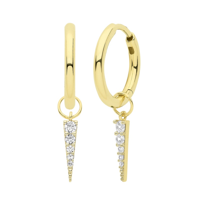 May include: A pair of gold hoop earrings with a dangling, pointed charm set with clear cubic zirconia stones.