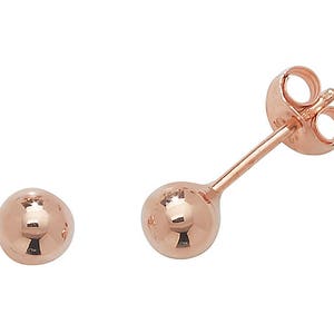 May include: A pair of rose gold stud earrings with round ball-shaped posts.