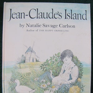 May include: A vintage children's book cover with the title "Jean-Claude's Island" by Natalie Savage Carlson. The cover features an illustration of a young person sitting with a cat in a field of flowers and a windmill in the background.