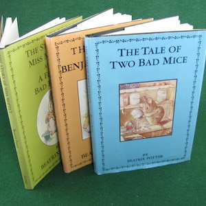 May include: Three vintage children's books by Beatrix Potter. The books are titled "The Story of Miss Moppet", "The Tale of Benjamin Bunny", and "The Tale of Two Bad Mice". The books have green, orange, and blue covers with illustrations of the characters.
