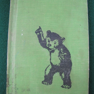 May include: A green book cover with a black and white illustration of a bear standing on its hind legs with its right paw raised. The text "BEAR" is printed in black at the bottom of the cover.