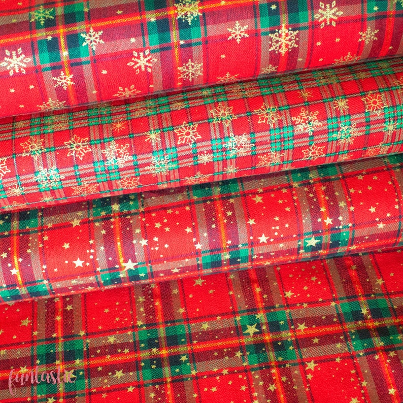 K&ouml;nnte beinhalten: Drei Rollen roter und gr&uuml;ner karierter Stoff mit goldenen Schneeflocken- und Sternenmustern. Der Stoff ist perfekt f&uuml;r Weihnachtsbastelarbeiten und -projekte.