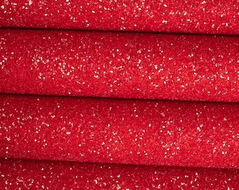 Op de afbeelding: Rode glitterstof met een fijne, glinsterende textuur. De stof is gevouwen in vier lagen, waardoor de diepte van de glitter zichtbaar wordt.