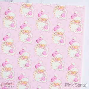 May include: Pink and white patterned fabric featuring a repeating design of Santa Claus holding a candy cane. The background is a light pink with a subtle snowflake pattern.