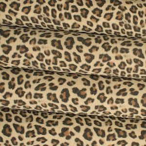 Op de afbeelding: Close-up van een beige stof met een bruin luipaardprintpatroon. De stof is in drieën gevouwen, waardoor het patroon zich herhaalt.