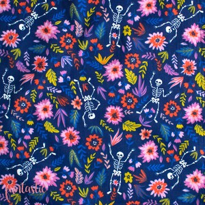 May include: A dark blue fabric with a repeating pattern of white skeletons dancing among pink, red, and yellow flowers. The background is a dark blue color.