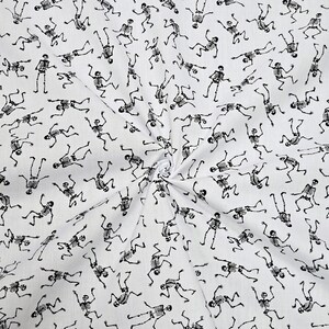 May include: White fabric with a repeating pattern of black skeletons dancing. The skeletons are in various poses and are all facing different directions.