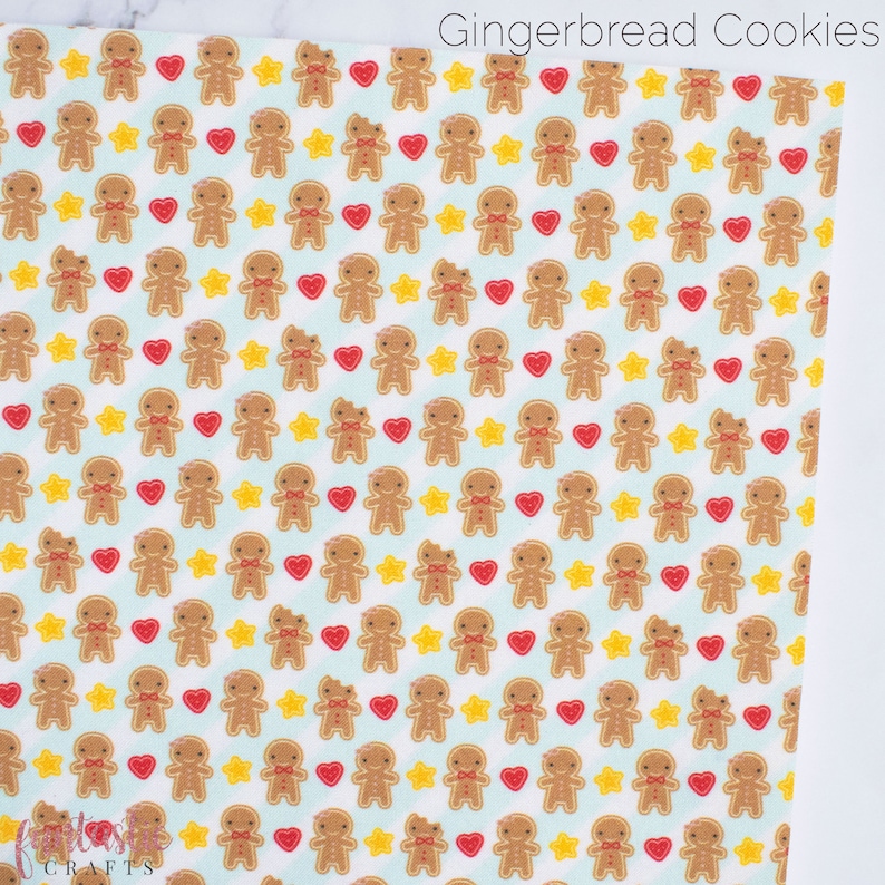 May include: A white fabric with a repeating pattern of gingerbread men, red hearts, and yellow stars. The background is a light blue color. The text "Gingerbread Cookies" is at the top of the image.