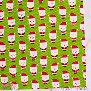 May include: Green fabric with a repeating pattern of white cartoon Santas wearing red hats. The fabric has a subtle white polka dot pattern.