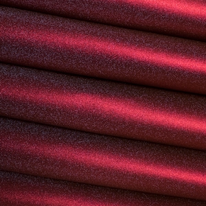 May include: Close-up of a deep red fabric with a sparkly, glittery texture. The fabric is folded in layers, creating a soft, luxurious look.