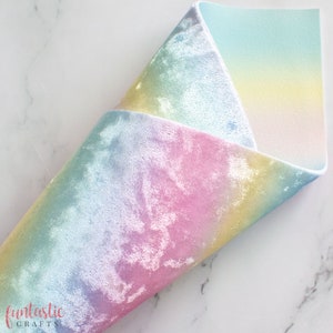 Peut inclure: Un morceau de tissu en velours arc-en-ciel iridescent plié avec un dégradé de couleurs bleu, rose et jaune.
