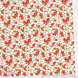 May include: White fabric with a repeating pattern of red and white roses, green leaves, and red berries. The fabric has the text "Christmas Floral" printed at the bottom.