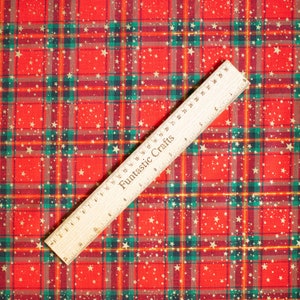 K&ouml;nnte beinhalten: Roter und gr&uuml;ner karierter Stoff mit goldenen Glitzersternen. Ein Holzlineal mit der Aufschrift "Funtastic Crafts" liegt auf dem Stoff.