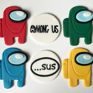 May include: Set of six fondant cake toppers featuring characters from the popular online game Among Us. The toppers are red, green, blue, yellow, and white with black outlines. The text "Among Us" and "...sus" are written on two of the toppers.