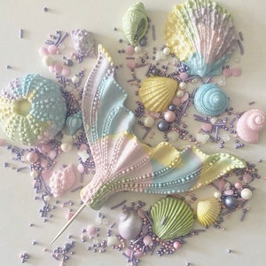 May include: Pastel coloured mermaid tail cake topper with a variety of pastel coloured seashells and sprinkles.