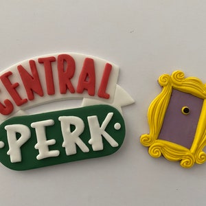 May include: White and red "Central Perk" sign with a green background and a yellow frame with a purple door. The sign is a popular prop from the TV show Friends.