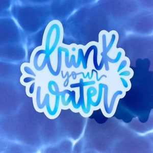 Könnte beinhalten: Ein blauer und weißer Aufkleber mit dem Text "drink your water" in einer stilisierten Schriftart. Der Aufkleber befindet sich auf einem blauen Hintergrund, der an Wasser erinnert.