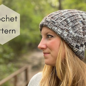 Può includere: Uno schema a uncinetto per un cappello beanie morbido. Il cappello è realizzato con un filato variegato in tonalità di marrone, grigio e bianco.