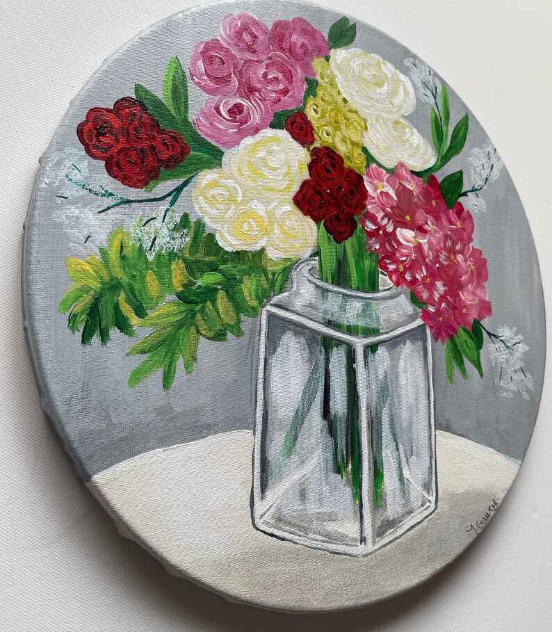 May include: A painting of a bouquet of flowers in a clear glass vase. The flowers are pink, white, red, and yellow. The vase is on a white surface. The background is gray.