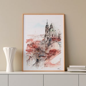 Op de afbeelding: Een aquarel schilderij van een stadsgezicht met een kerk op de achtergrond. Het schilderij is ingelijst in een licht houten lijst en hangt aan een muur.