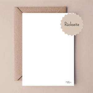May include: A blank white rectangular card partially inserted into a brown kraft paper envelope. A beige scalloped circular sticker with the black text R&uuml;ckseite is positioned in the upper right corner. A small black logo is at the bottom right.
