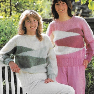 Könnte beinhalten: Zwei Frauen tragen Pullover mit geometrischem Muster. Der Pullover links ist weiß mit grünen und blauen Streifen. Der Pullover rechts ist rosa mit weißen und rosa Streifen.