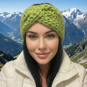Könnte beinhalten: Ein hellgrünes, grob gestricktes Stirnband. Das Stirnband hat ein verdrehtes Design und besteht aus einem dicken, strukturierten Garn. Dieses Accessoire soll die Ohren warm halten und jedem Outfit einen Farbtupfer verleihen.