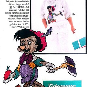Könnte beinhalten: Ein weißer Strickpullover mit einem bunten gestickten Bild von Pinocchio. Der Pullover hat einen roten Hut, eine lila Hose und ein grünes Hemd. Der Text "Liebenswerter Lügner: PINOCCHIO" ist unter dem Bild gedruckt.