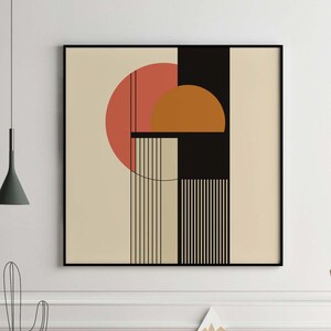 Könnte beinhalten: Abstrakter geometrischer Kunstdruck in einem schwarzen Rahmen. Das Kunstwerk zeigt einen großen roten Kreis, einen kleineren orangefarbenen Halbkreis und schwarze und beige rechteckige Formen mit vertikalen Linien. Der Druck hängt über einem Holztisch mit dekorativen Gegenständen.