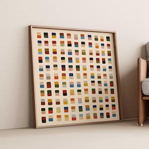 May include: A square framed wall art piece featuring a grid of small, vertically stacked rectangular colour blocks in shades of red, blue, yellow, green, black, and pink on a cream background, housed in a simple light brown wooden frame.