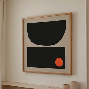 May include: Abstract art print in a wooden frame. The artwork features a black semi-circle above a black rectangle, with a small orange circle on the bottom right. The background is a light beige color.